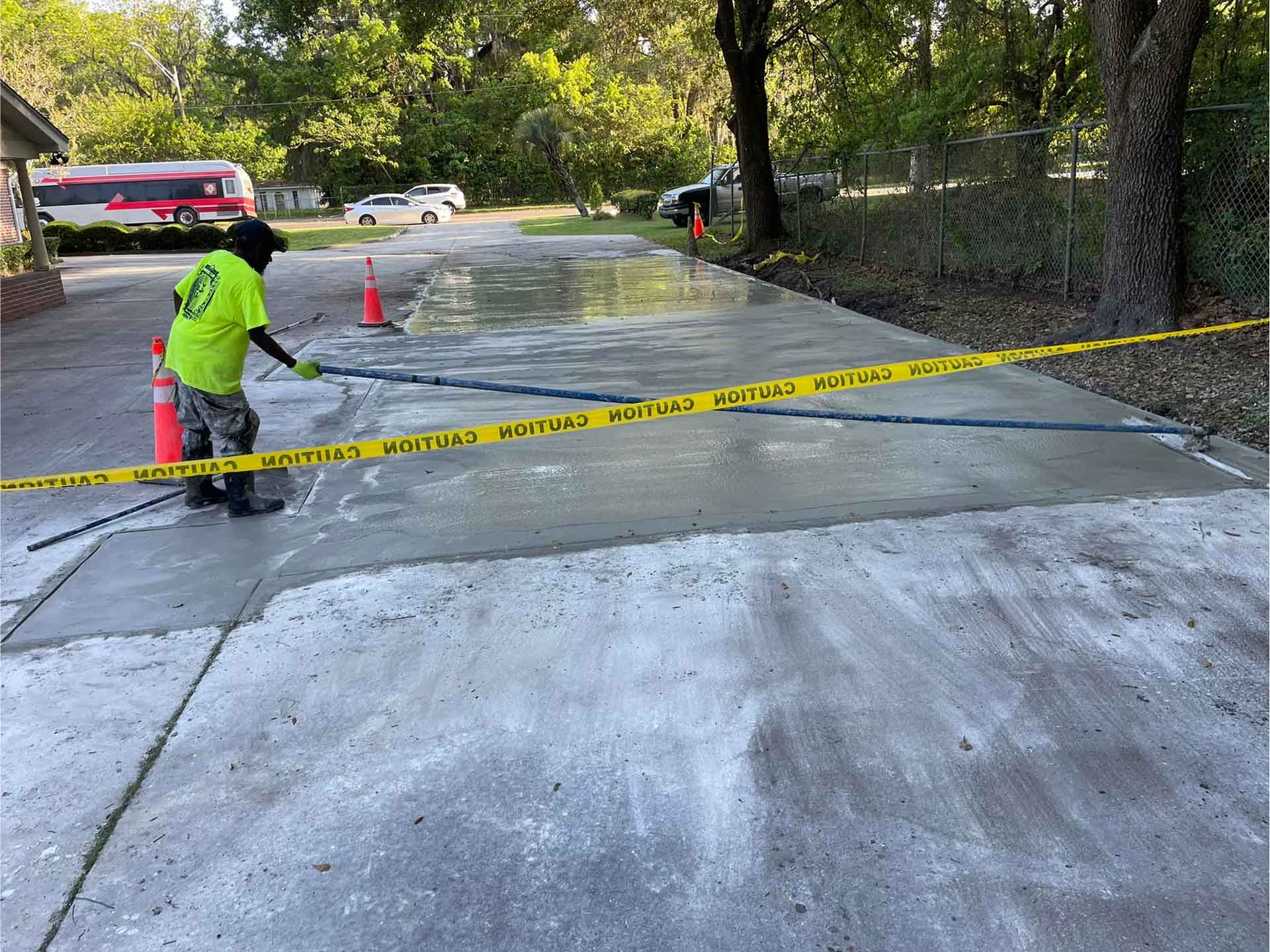 Worker from Ernest Concrete smoothing newly poured concrete in a parking lot